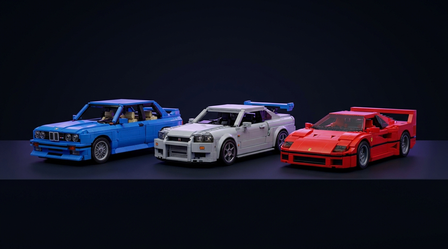 Three LEGO brick-built car models — BMW M3 E30, Nissan Skyline R34, and Ferrari F40 — displayed on a dark navy surface